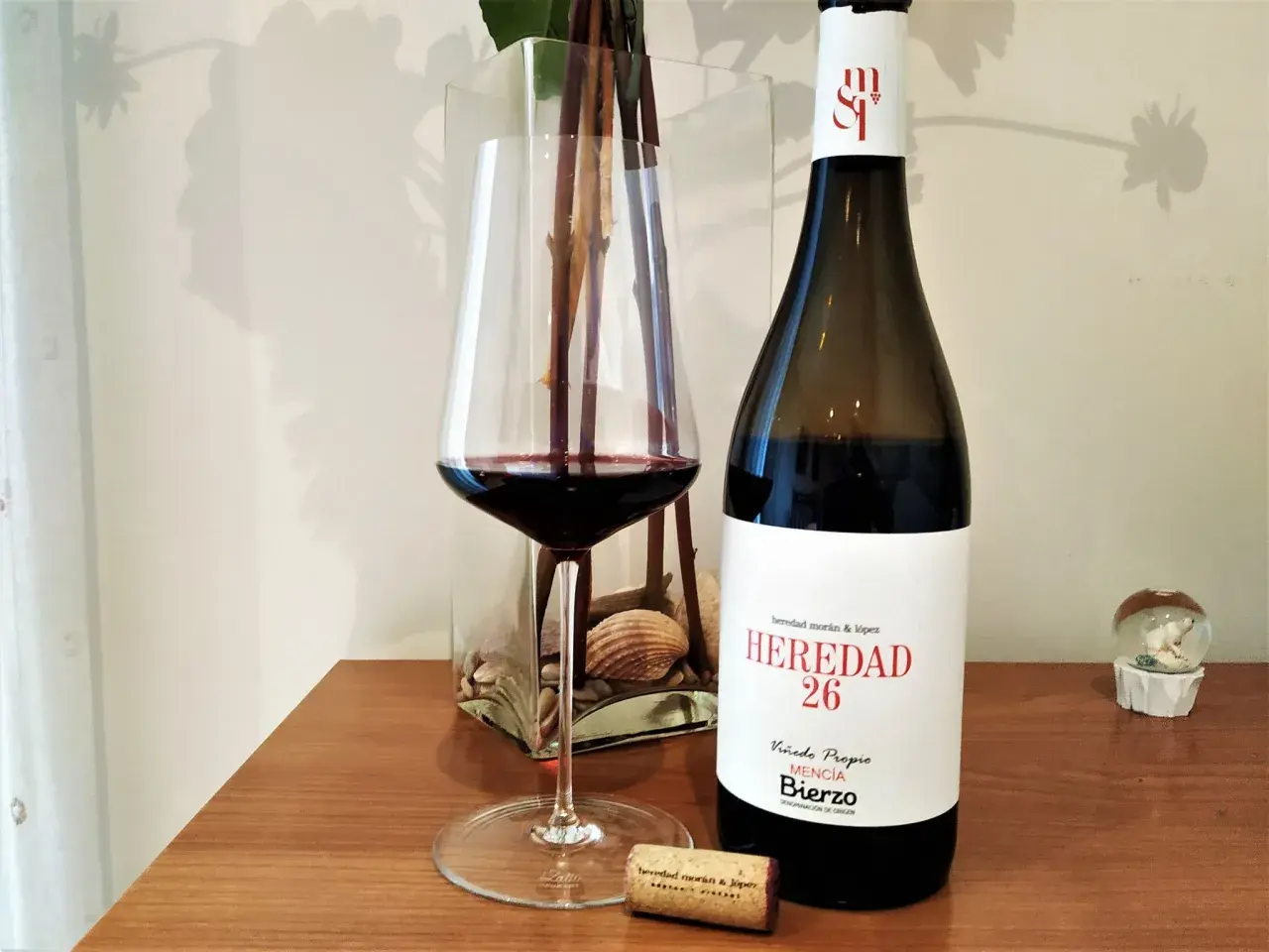 Una copa de vino tinto junto a una botella de vino del Bierzo. El corcho yace cerca, listo para otra degustación.