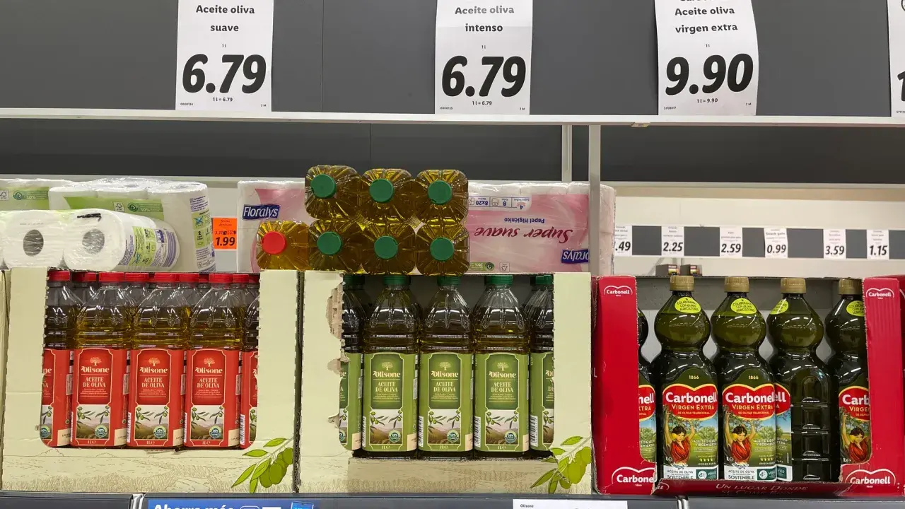 Estanterías de supermercado con varias botellas de aceite de oliva. El precio del aceite de oliva suave es de 6.79, el intenso también 6.79 y el virgen extra 9.90.