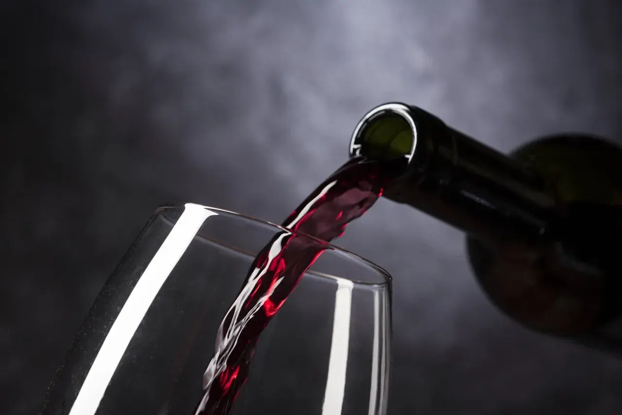 Vino tinto de Rioja o Ribera del Duero vertiéndose de una botella a una copa, creando un momento de placer.