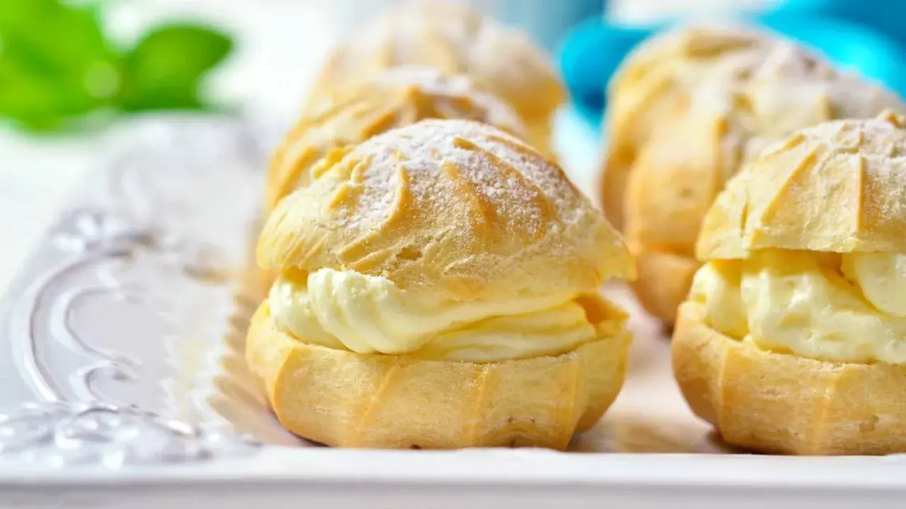 Profiteroles rellenos de crema pastelera Thermomix, espolvoreados con azúcar glas. Deliciosos y fáciles de preparar.