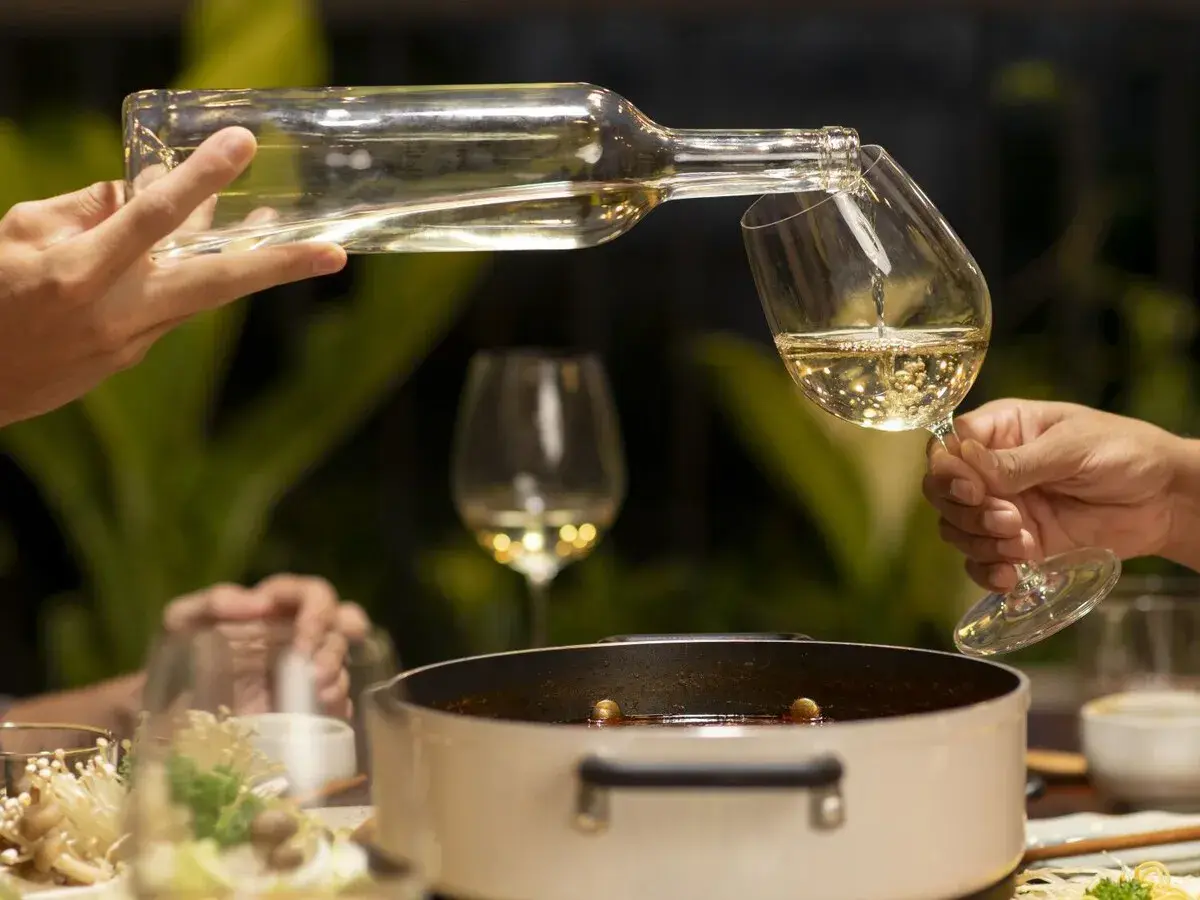 Sirviendo vino blanco fresco en copas, perfecto para acompañar una cena con amigos.