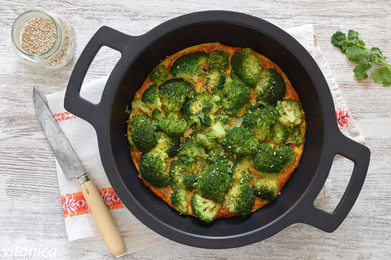 Tortilla de brócoli recién horneada, adornada con semillas de sésamo y perejil, lista para servir.