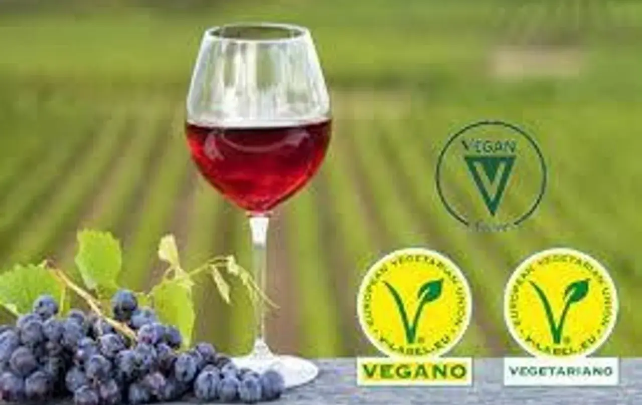 Copa de vino tinto junto a uvas. Sellos vegano y vegetariano indican porque el vino no es vegano.