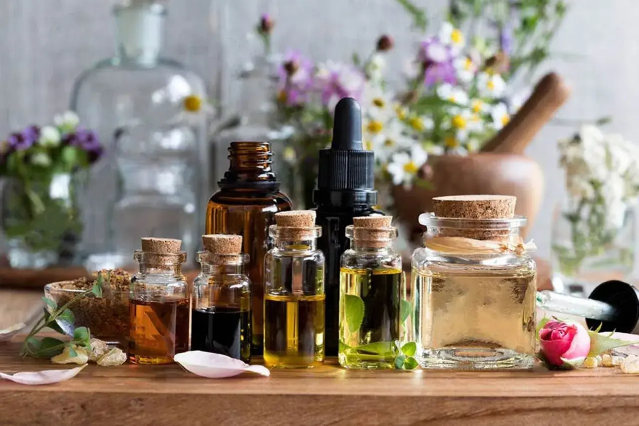 Varias botellas de aceites esenciales, algunas con hierbas y flores, sugieren el mejor aceite para la circulación.