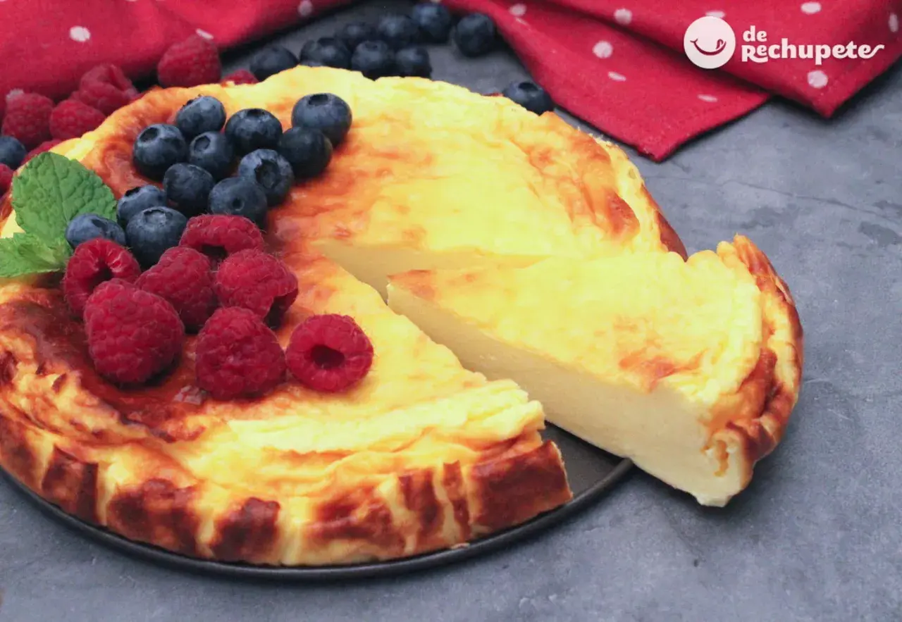 Tarta de yogur griego dorada, decorada con frambuesas y arándanos frescos. ¡Un postre irresistible!