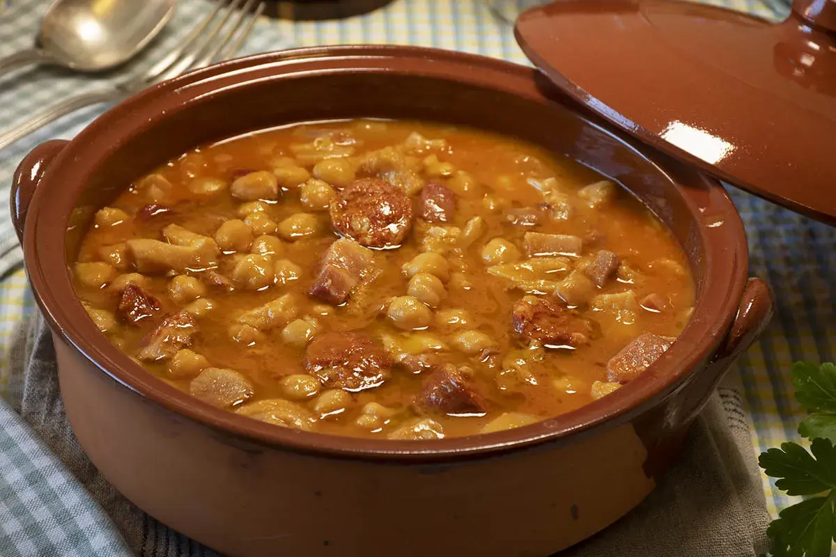 Un plato humeante de callos a la gallega, con garbanzos, chorizo y trozos de carne en una cazuela de barro.