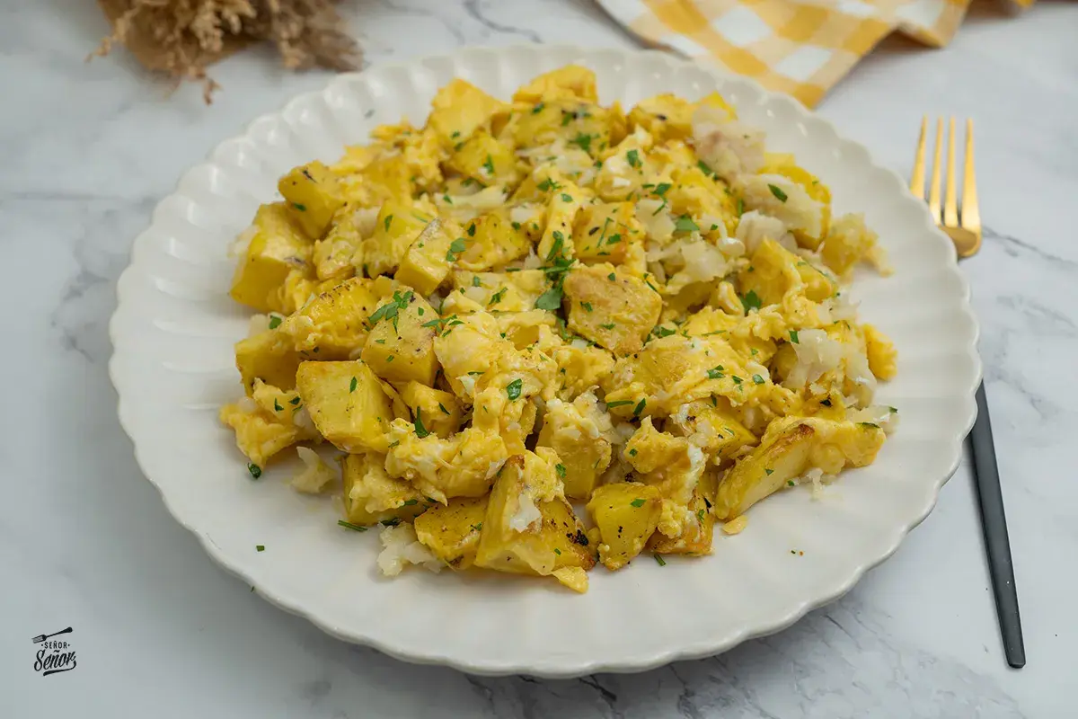 Un delicioso revuelto de bacalao con patatas, espolvoreado con perejil fresco. Un plato casero perfecto para cualquier momento del día.