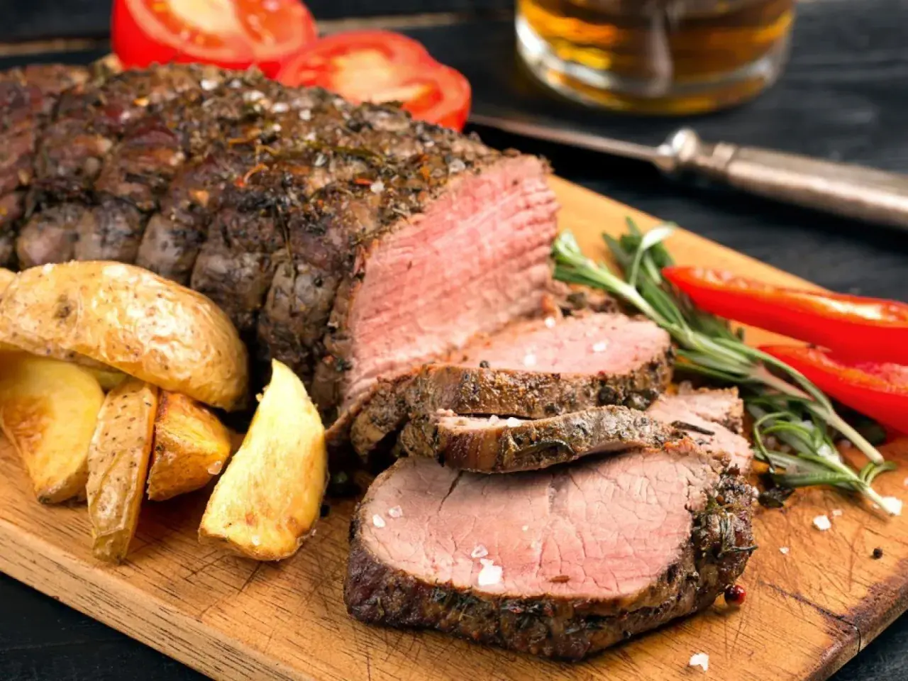 Jugosa carne asada, perfectamente cocida, acompañada de papas rústicas, rodajas de tomate y pimientos rojos. ¡Un festín para los sentidos!