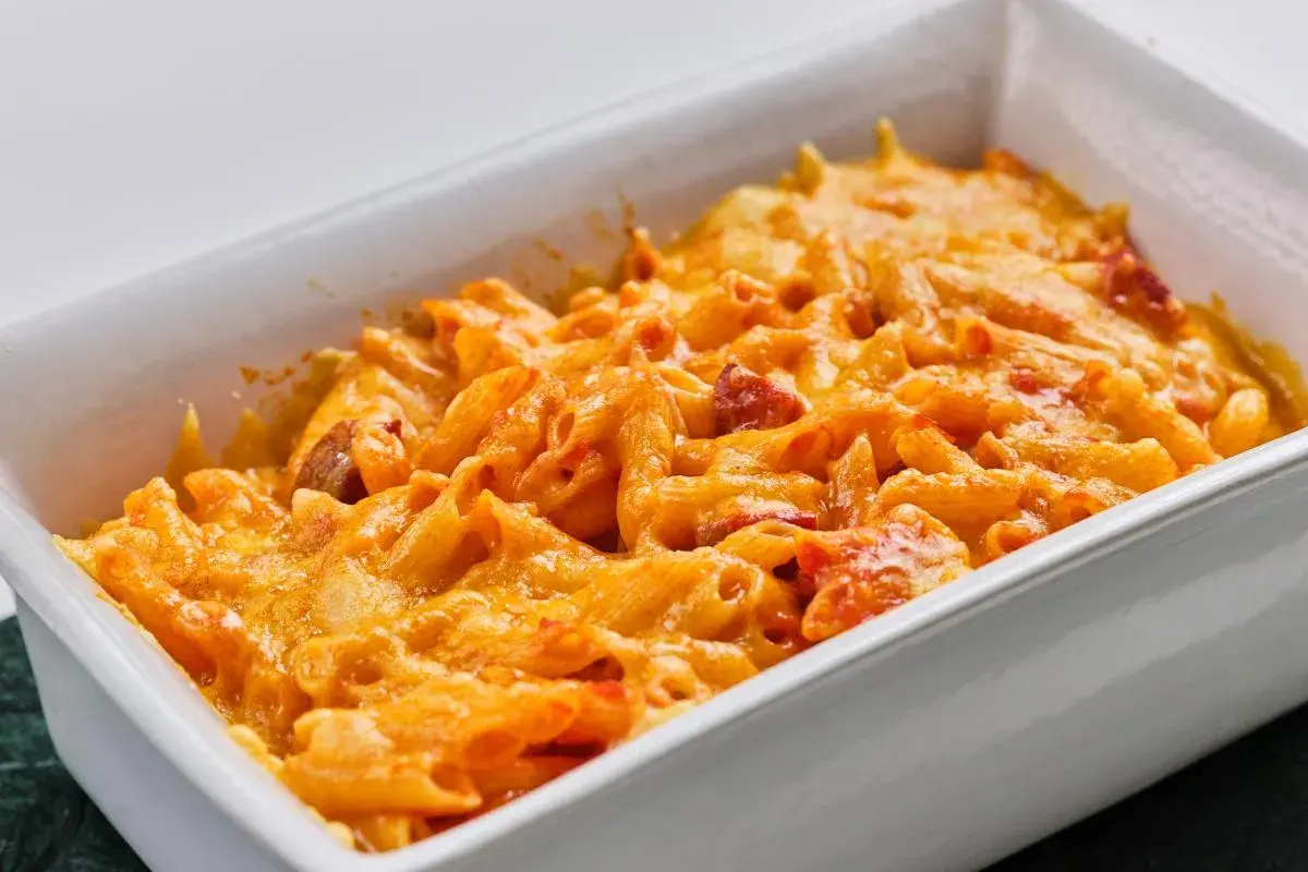 Macarrones con chorizo gratinados, cubiertos de queso derretido y burbujeante en una fuente blanca.