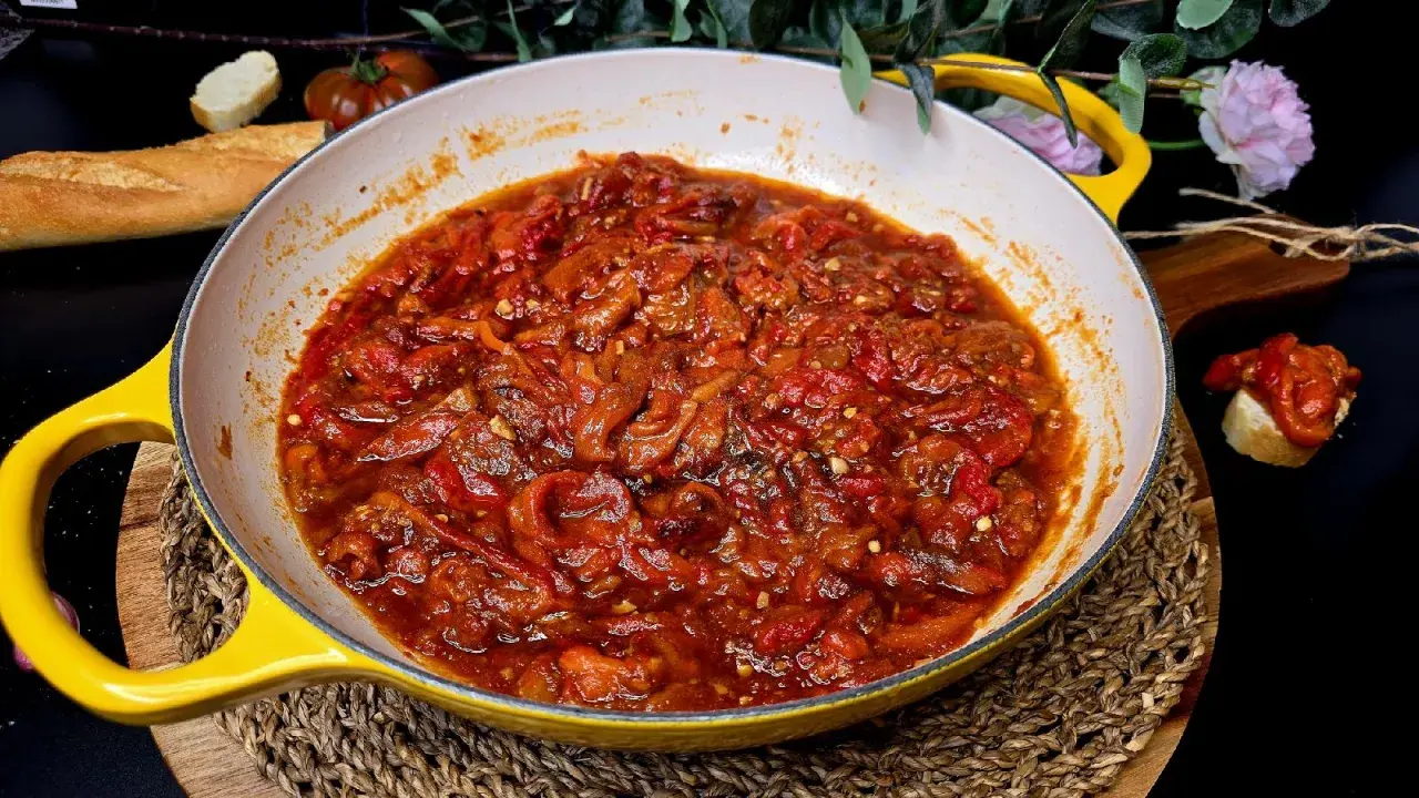 Asadillo manchego recién hecho en sartén amarilla, acompañado de pan y tomates.