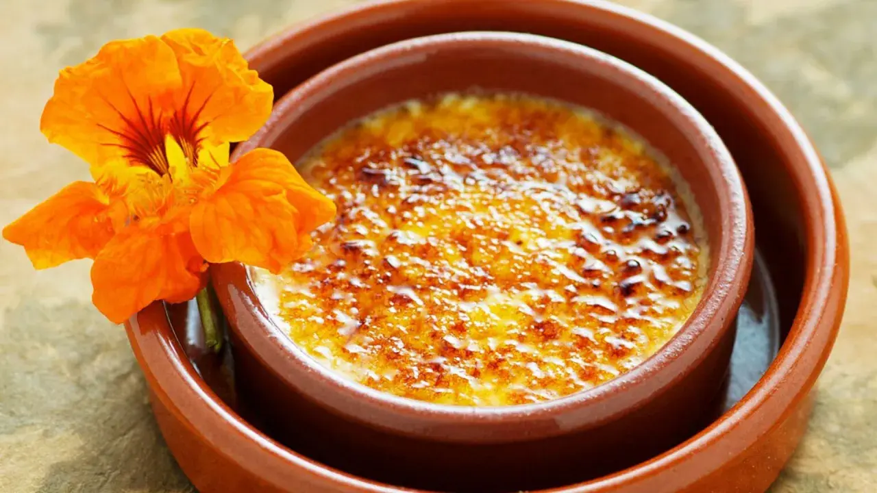 Crema catalana con una flor naranja. Una delicia para tu crema catalana receta.