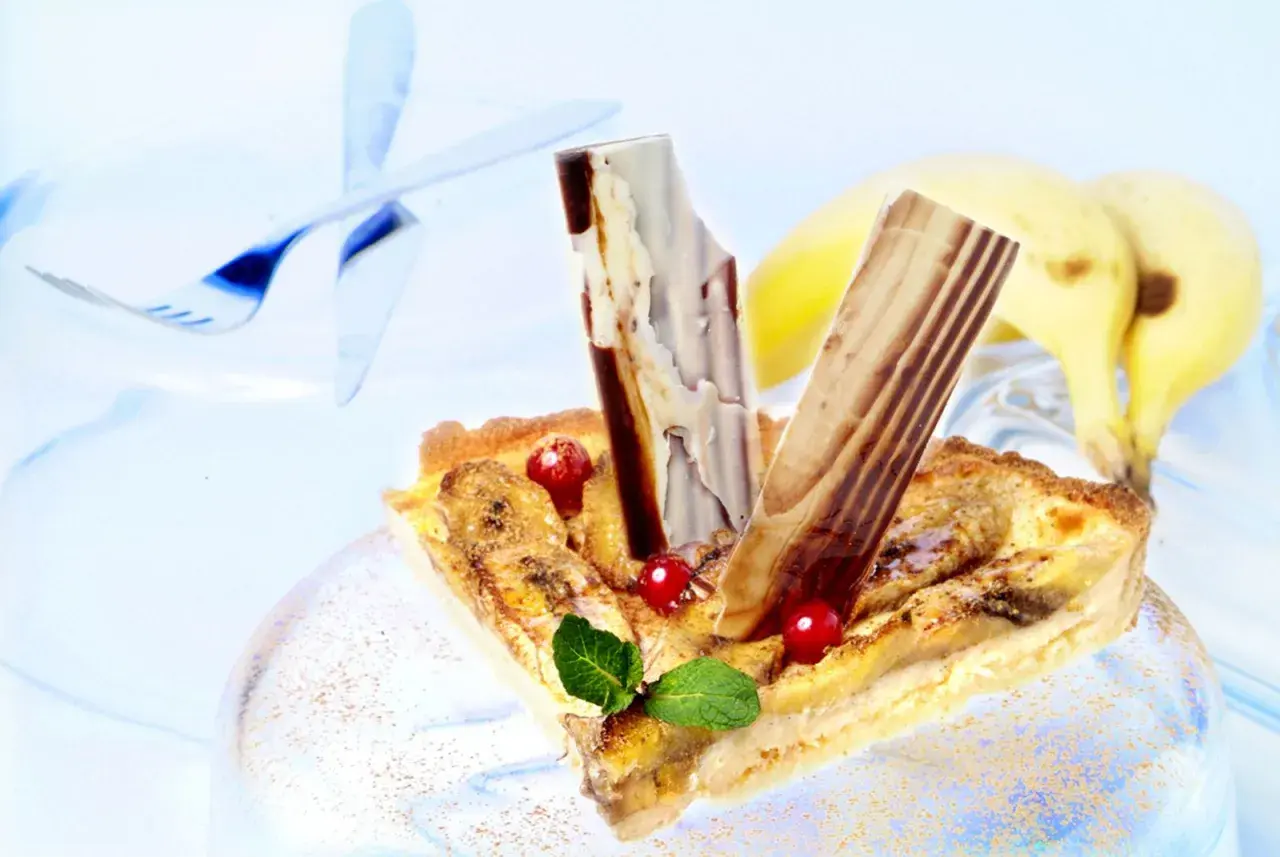 Deliciosa tarta de plátano con trozos de chocolate y frutos rojos, lista para disfrutar.
