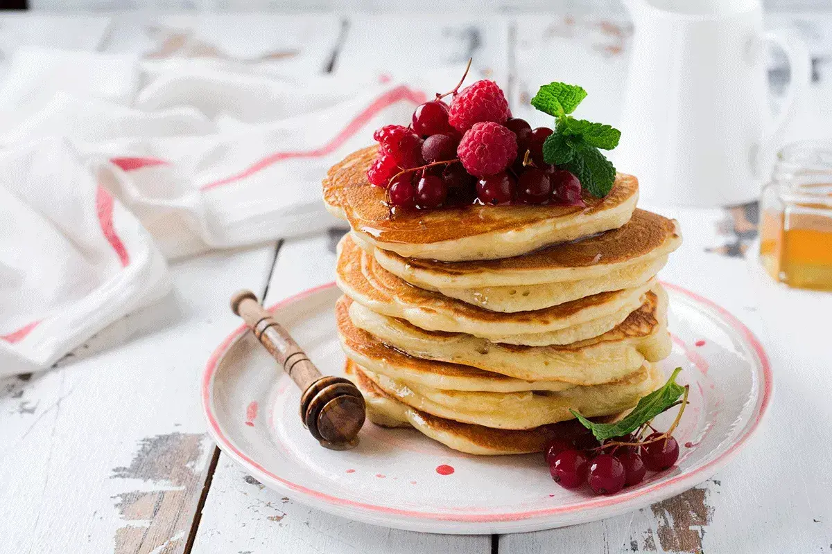 Deliciosas tortitas de avena apiladas, cubiertas con frutos rojos y menta. Un desayuno perfecto para empezar el día.