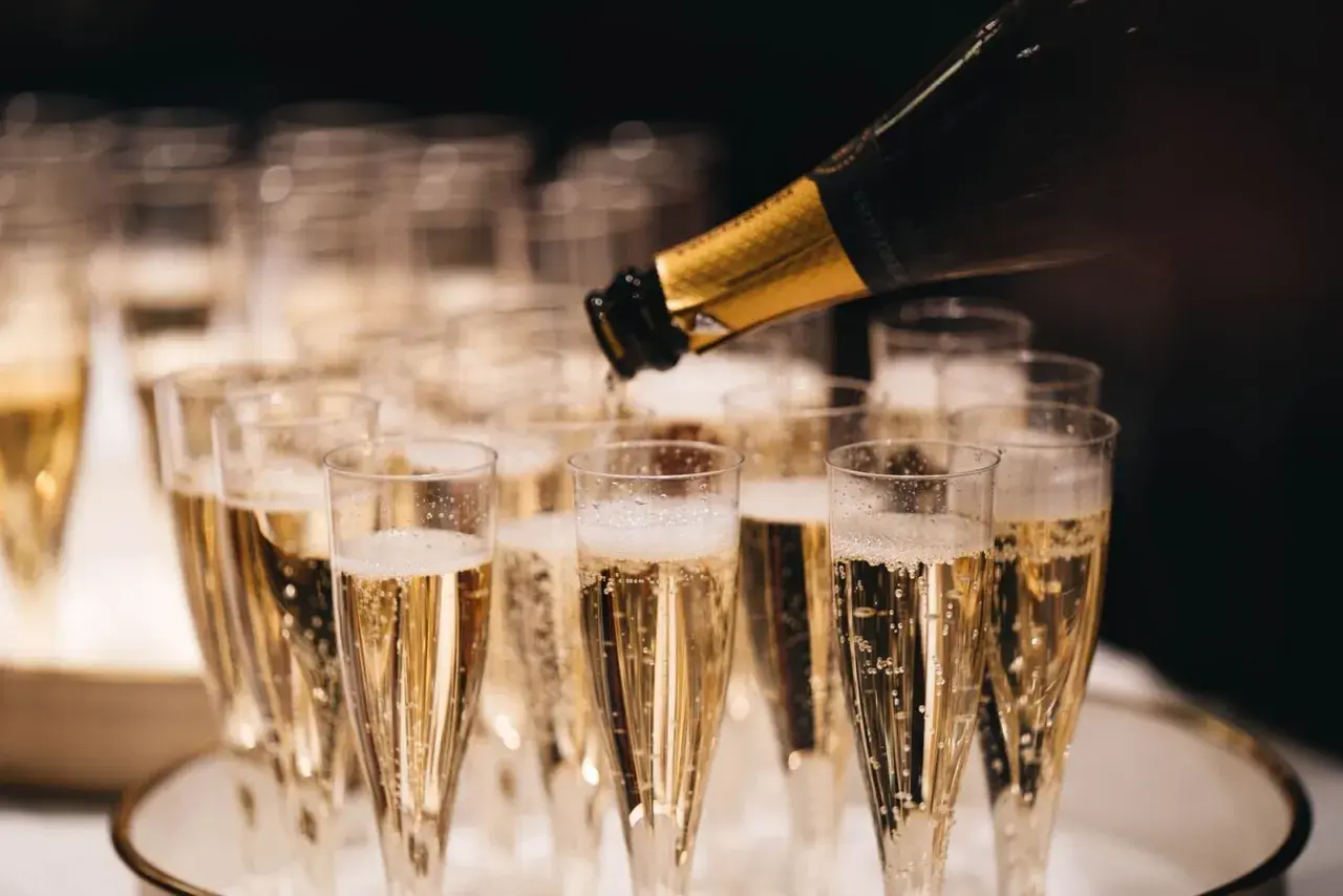 Servicio de cava más caro, burbujas doradas llenando copas para una celebración especial.