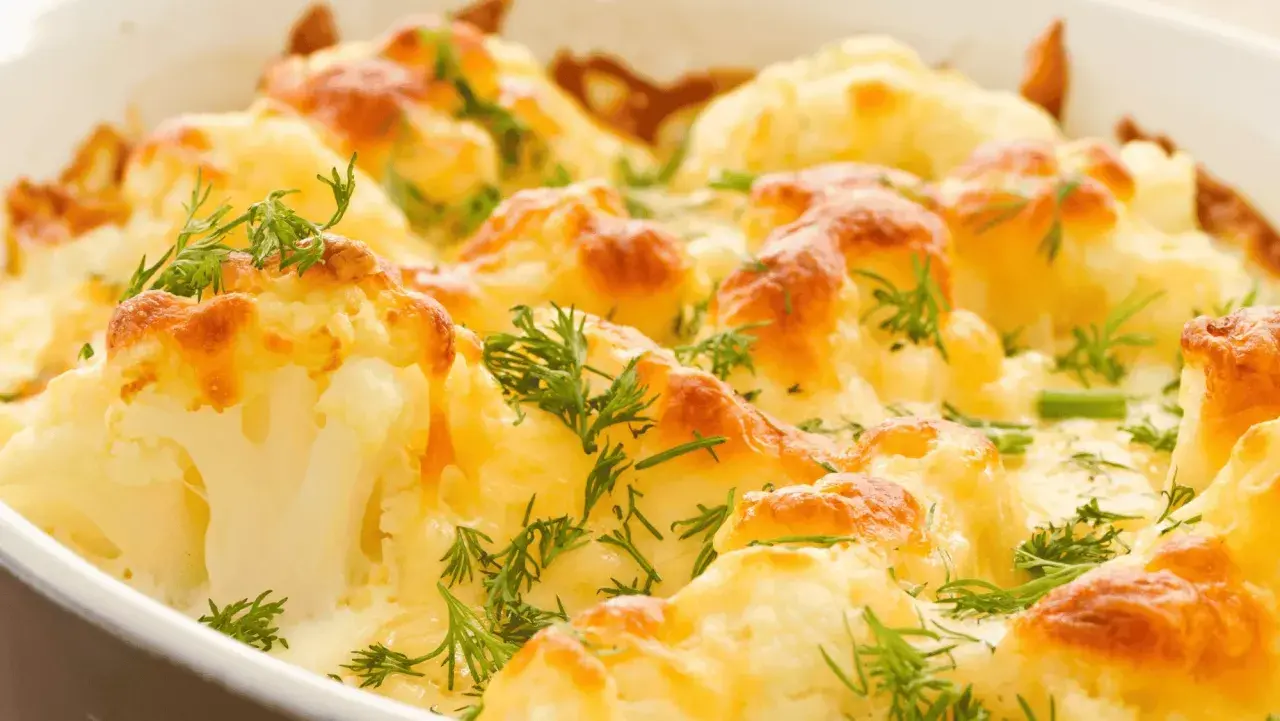 Coliflor al horno gratinada con queso y hierbas frescas, un plato reconfortante y delicioso.