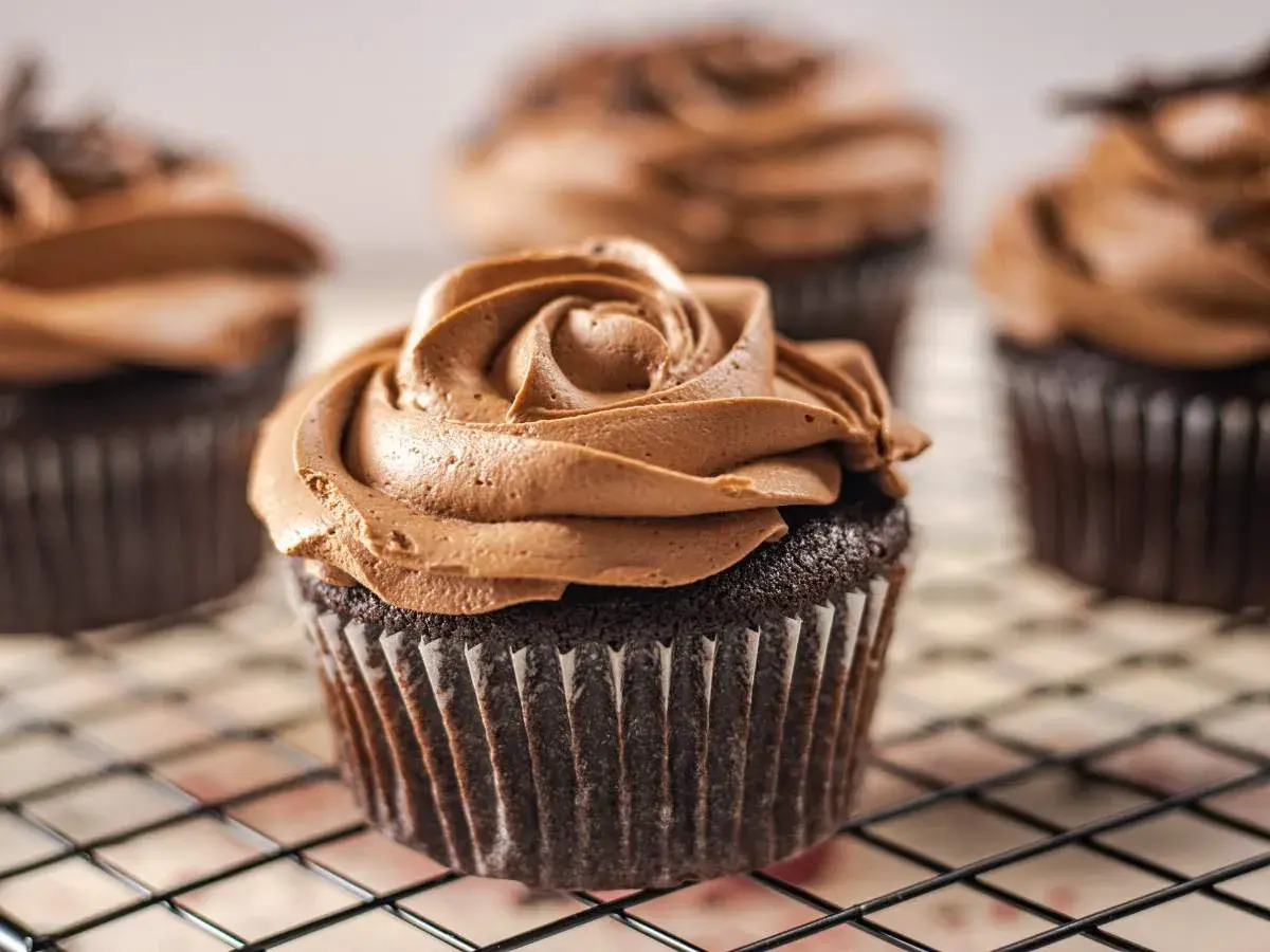 Deliciosas magdalenas sin huevo con glaseado de chocolate cremoso, dispuestas en una rejilla.