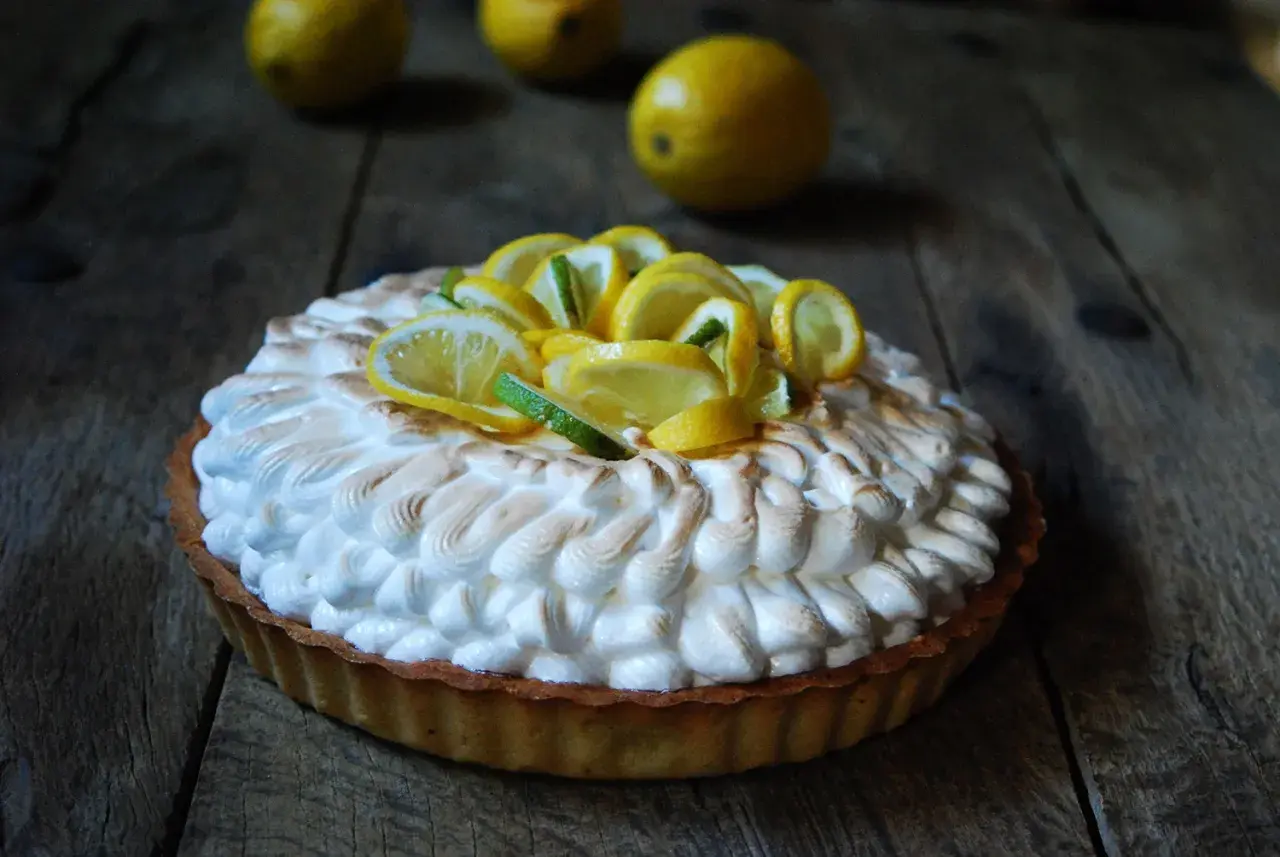 Deliciosa tarta de limón con merengue dorado y rodajas de limón fresco.