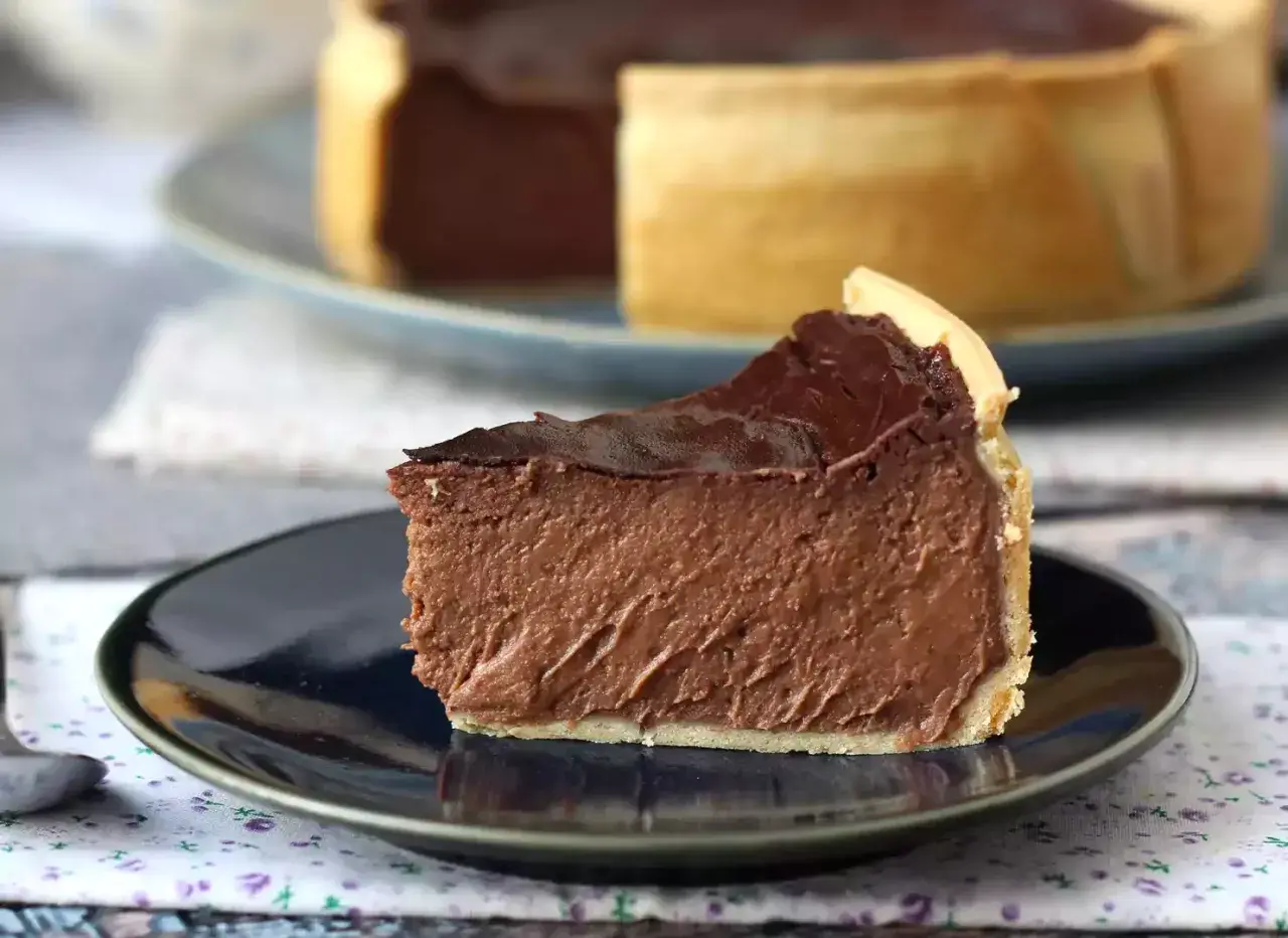 Rebanada de flan de chocolate con cobertura brillante y base dorada, servida en plato oscuro.