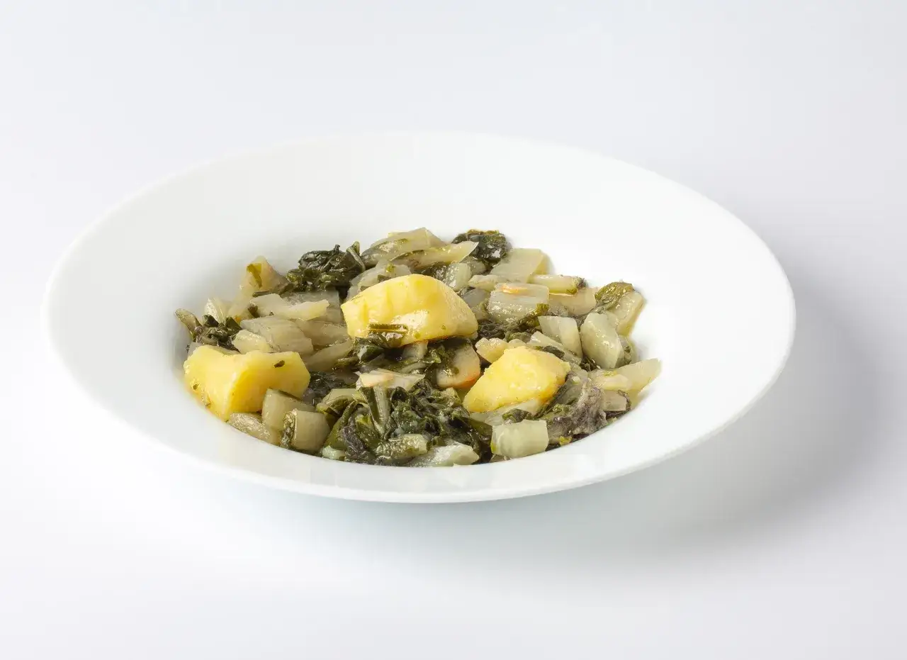 Un plato blanco con acelgas con patatas, un guiso casero y reconfortante.