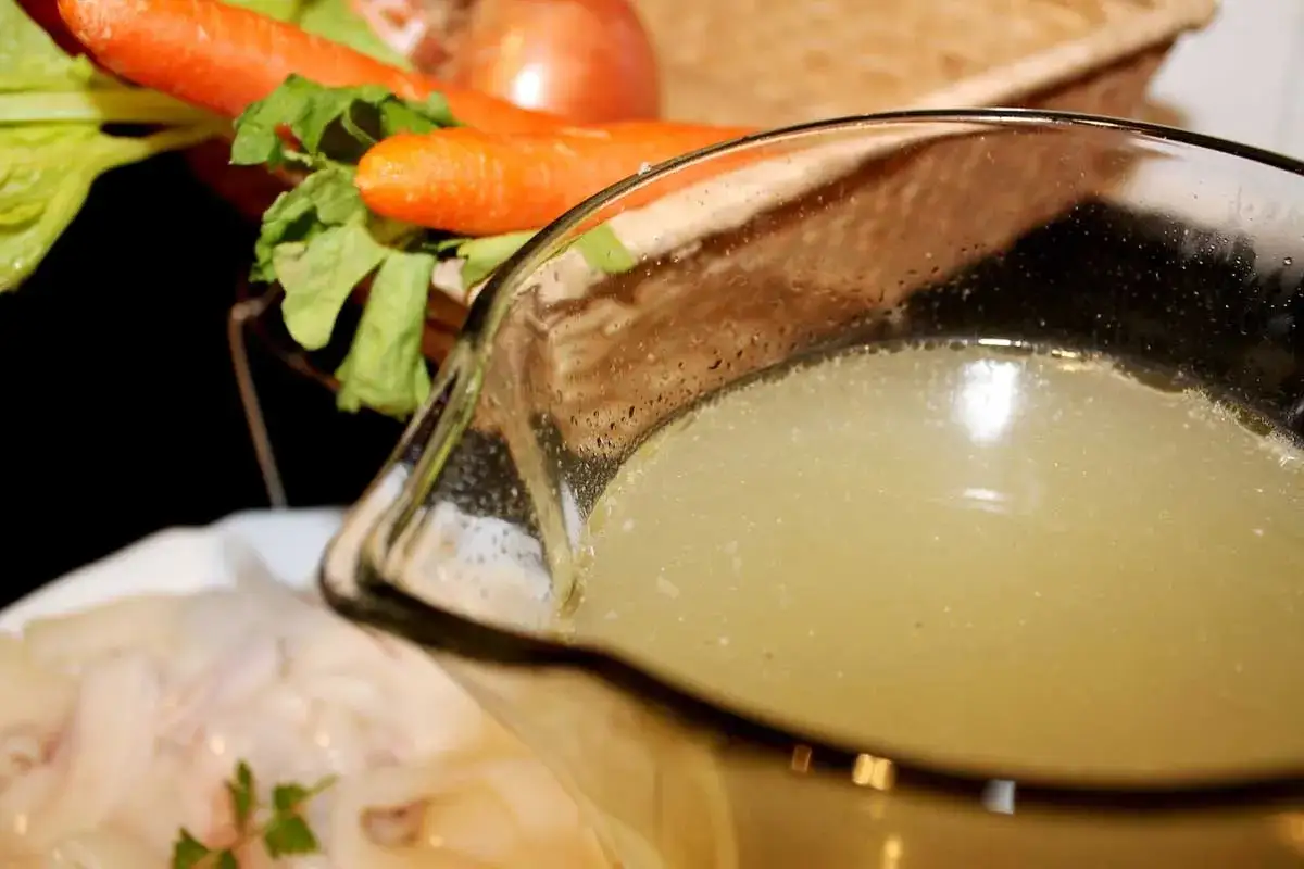 Caldo de pescado casero listo para usar. Zanahorias, apio y cebolla en el fondo.