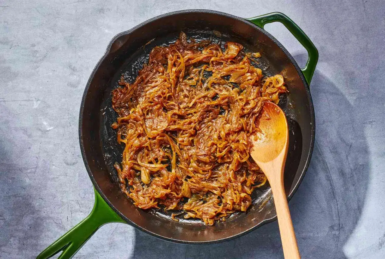 Cebolla caramelizada dorada y tierna en sart&eacute;n de hierro fundido, lista para a&ntilde;adir sabor a cualquier plato.