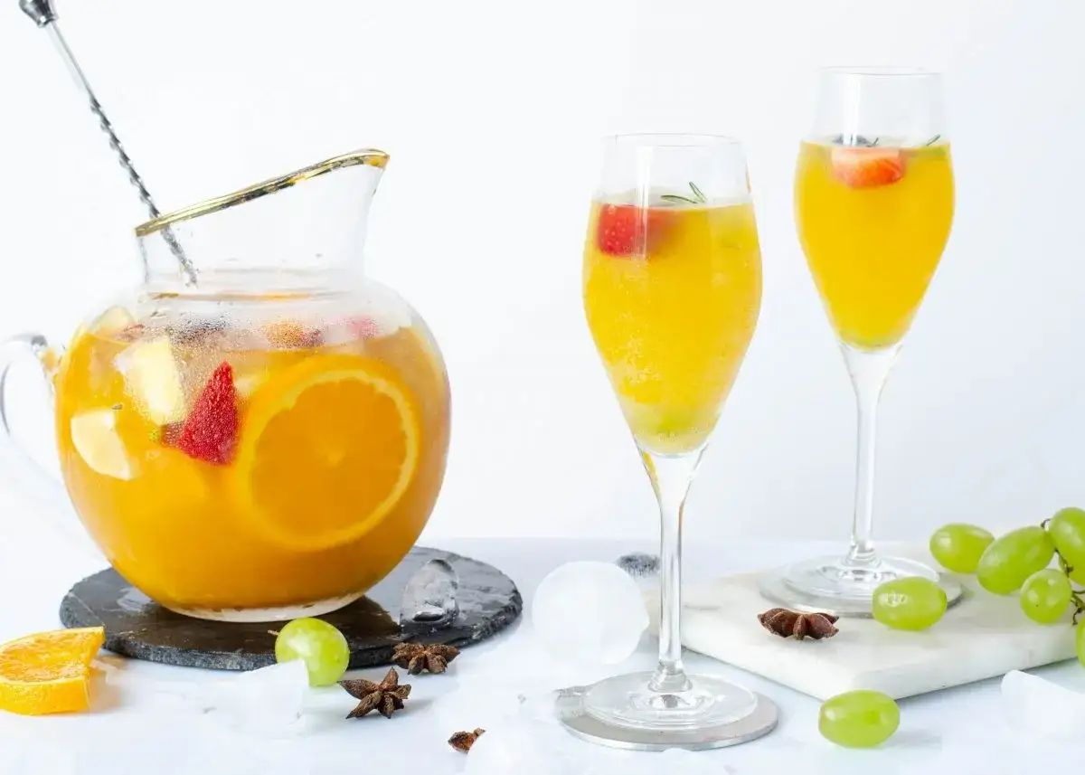 Jarra y copas de sangría de cava con frutas frescas, hielo y anís estrellado. ¡Perfecta para un brindis refrescante!
