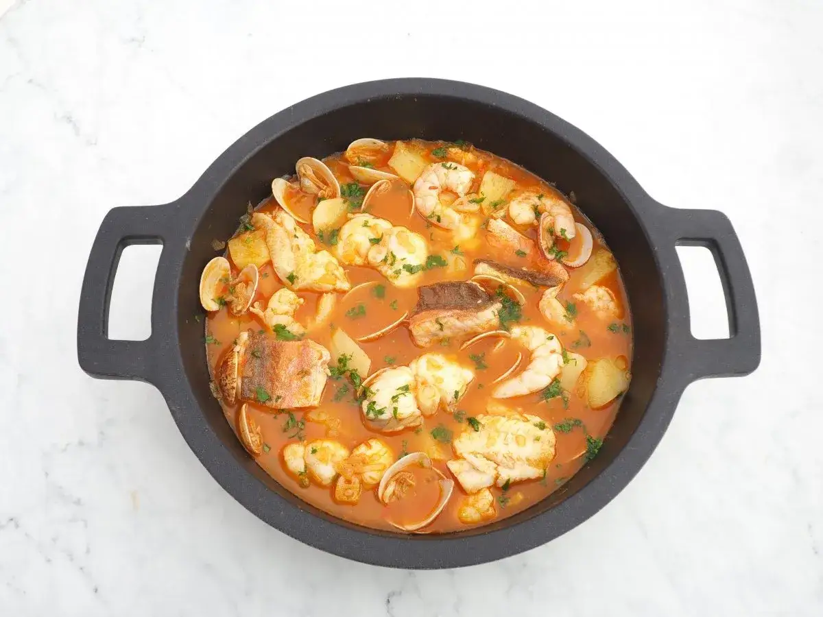Caldereta de pescado con patatas, gambas y almejas, un plato reconfortante y lleno de sabor marino.