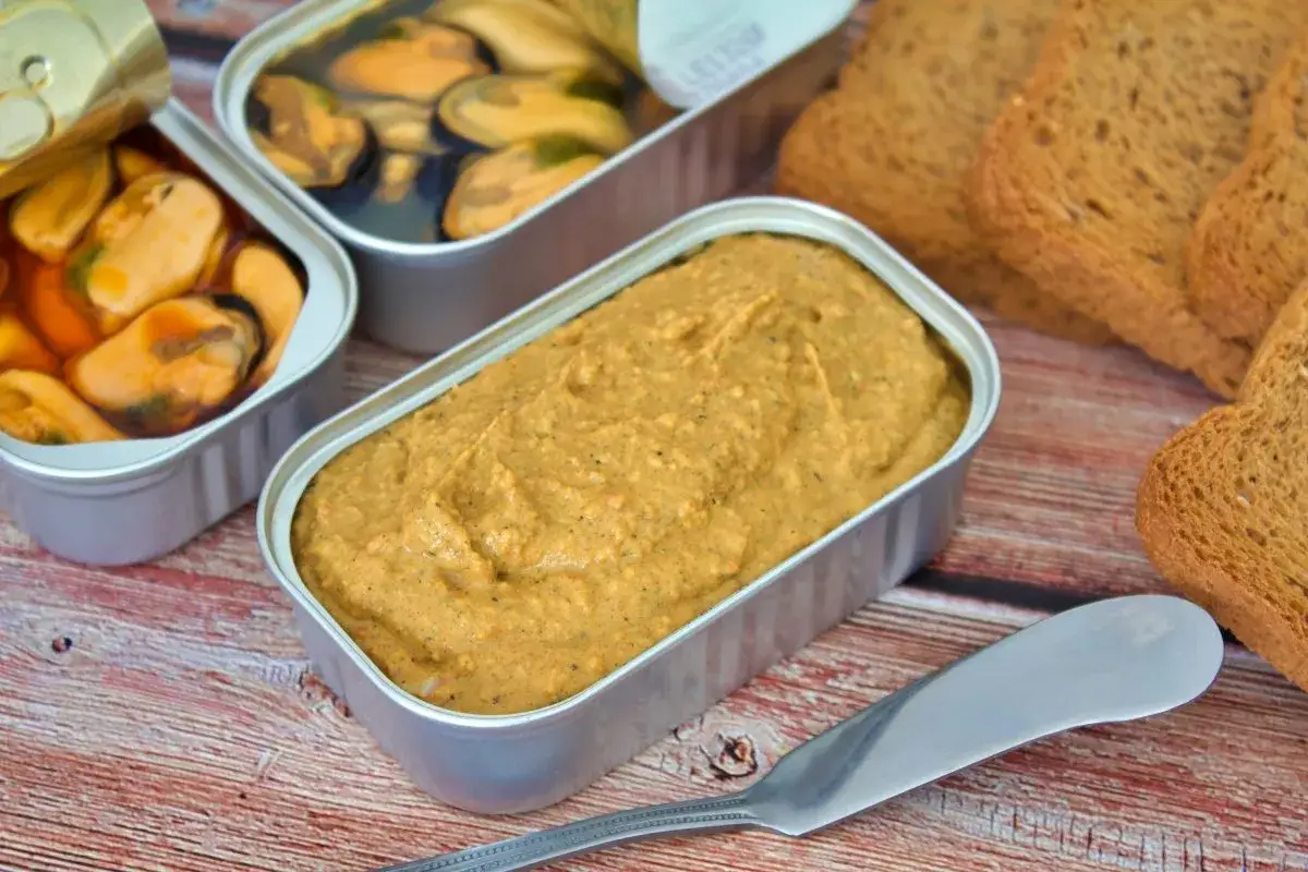 Pate de mejillones en lata, junto a mejillones al natural y tostadas.