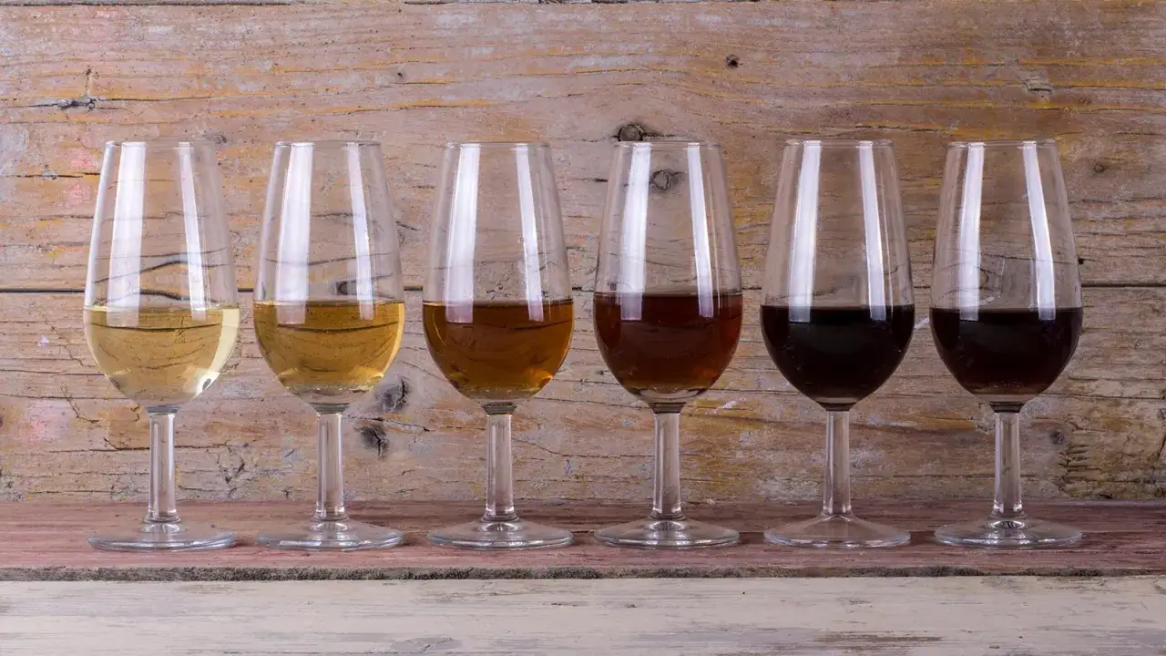 Seis copas de vino con diferentes tonalidades, desde doradas hasta oscuras, mostrando la variedad de un vino generoso.