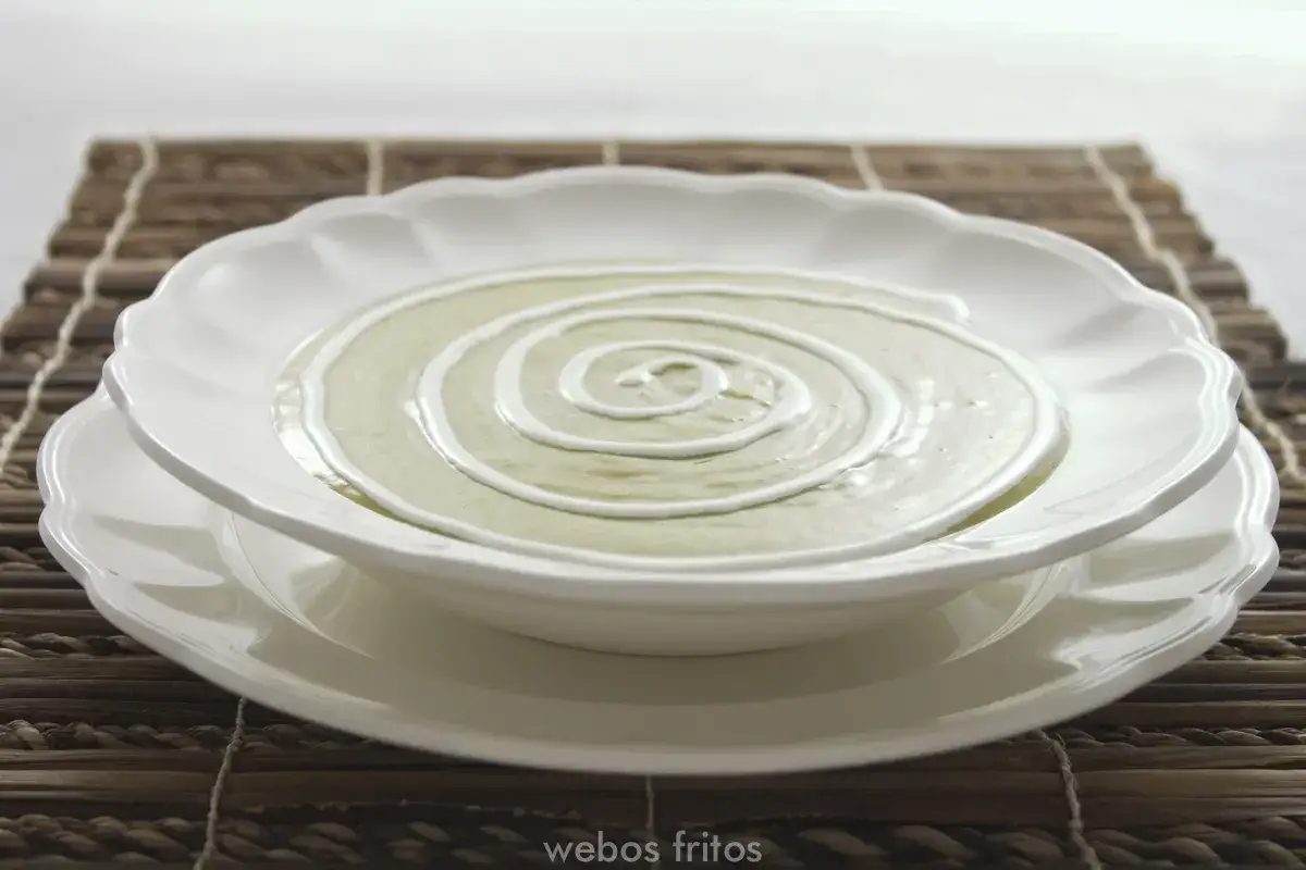 Crema de esp&aacute;rragos servida en un plato blanco con un remolino de nata.
