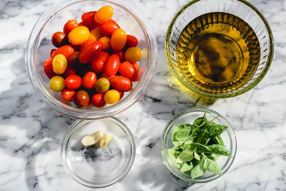 Ingredientes para tomates cherry confitados: tomates variados, aceite de oliva, ajo y albahaca fresca.