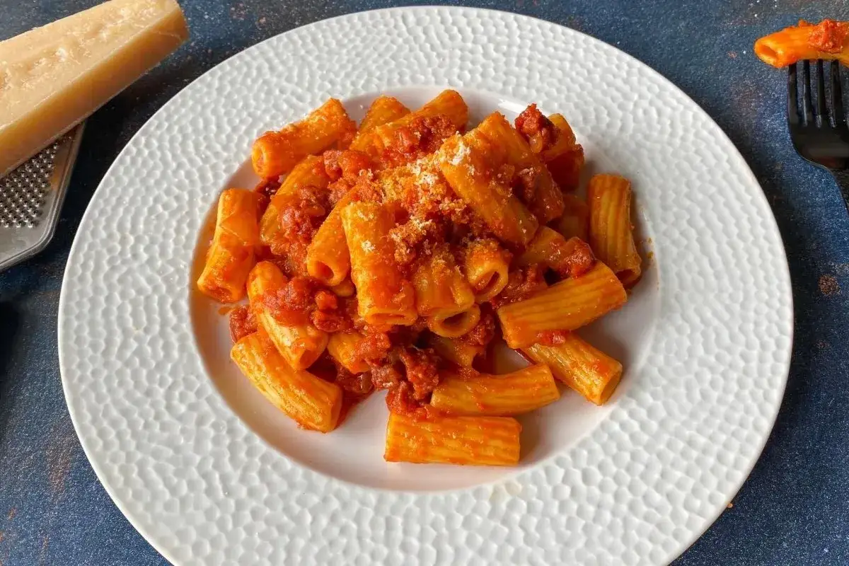 Un plato de macarrones con chorizo, cubiertos con una rica salsa de tomate y espolvoreados con queso rallado.