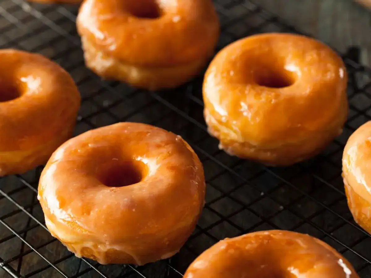 Deliciosos donuts caseros glaseados, reci&eacute;n hechos y enfri&aacute;ndose en una rejilla.