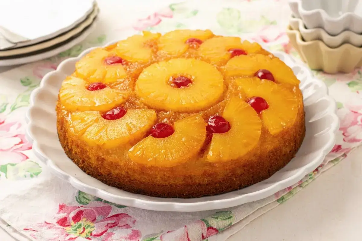 Deliciosa tarta de pi&ntilde;a con rodajas de pi&ntilde;a caramelizada y cerezas rojas en la parte superior, lista para ser disfrutada.