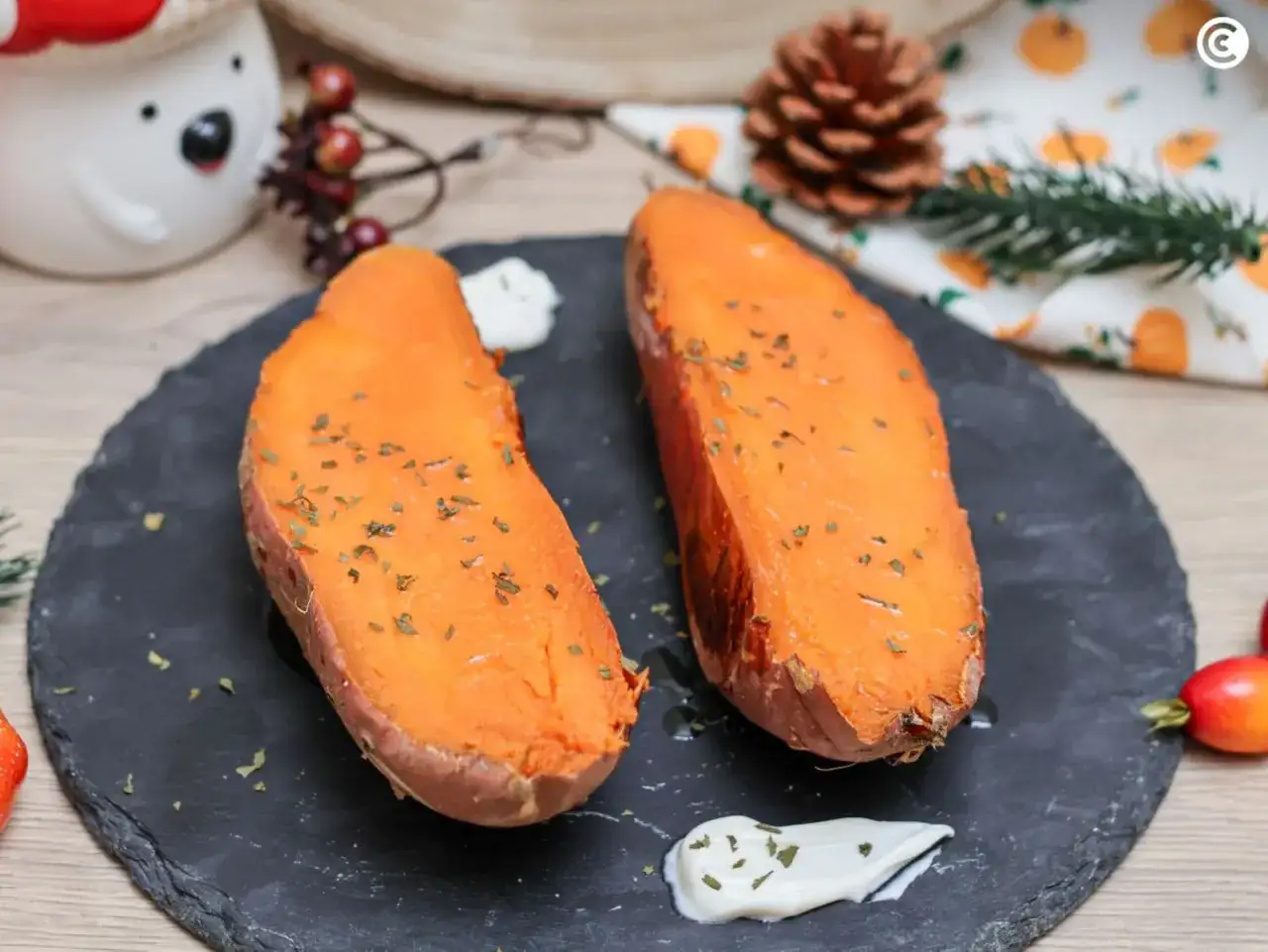 Dos mitades de boniato al horno, tiernas y doradas, espolvoreadas con hierbas. Servidas con una cucharada de crema.