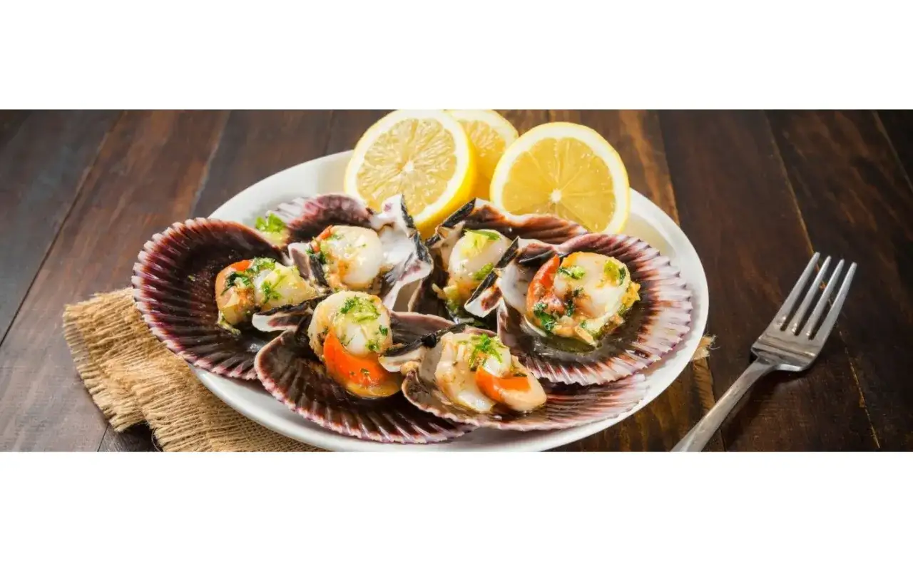 Deliciosas zamburiñas a la plancha, servidas en sus conchas con limón y perejil. Un manjar listo para disfrutar.