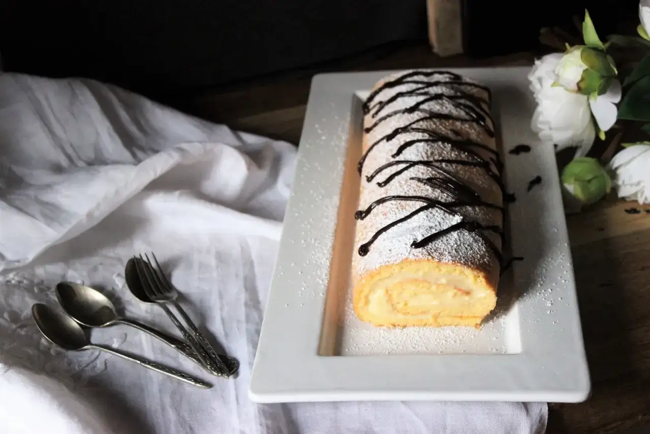 Un delicioso brazo de gitano cubierto de az&uacute;car glas y chocolate, listo para ser disfrutado.