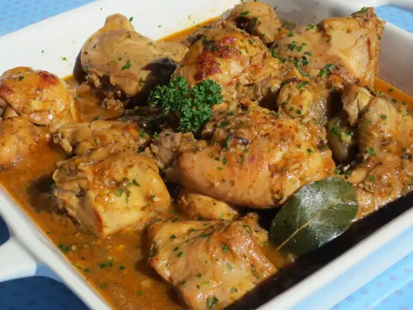 Delicioso conejo guisado en salsa dorada, con perejil picado y una hoja de laurel.